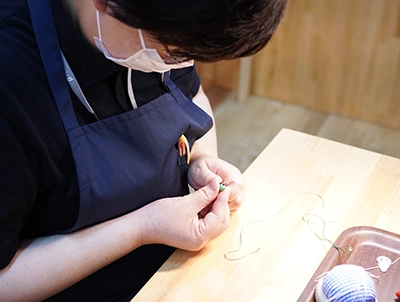 画像：絹糸でアクセサリーを制作している様子